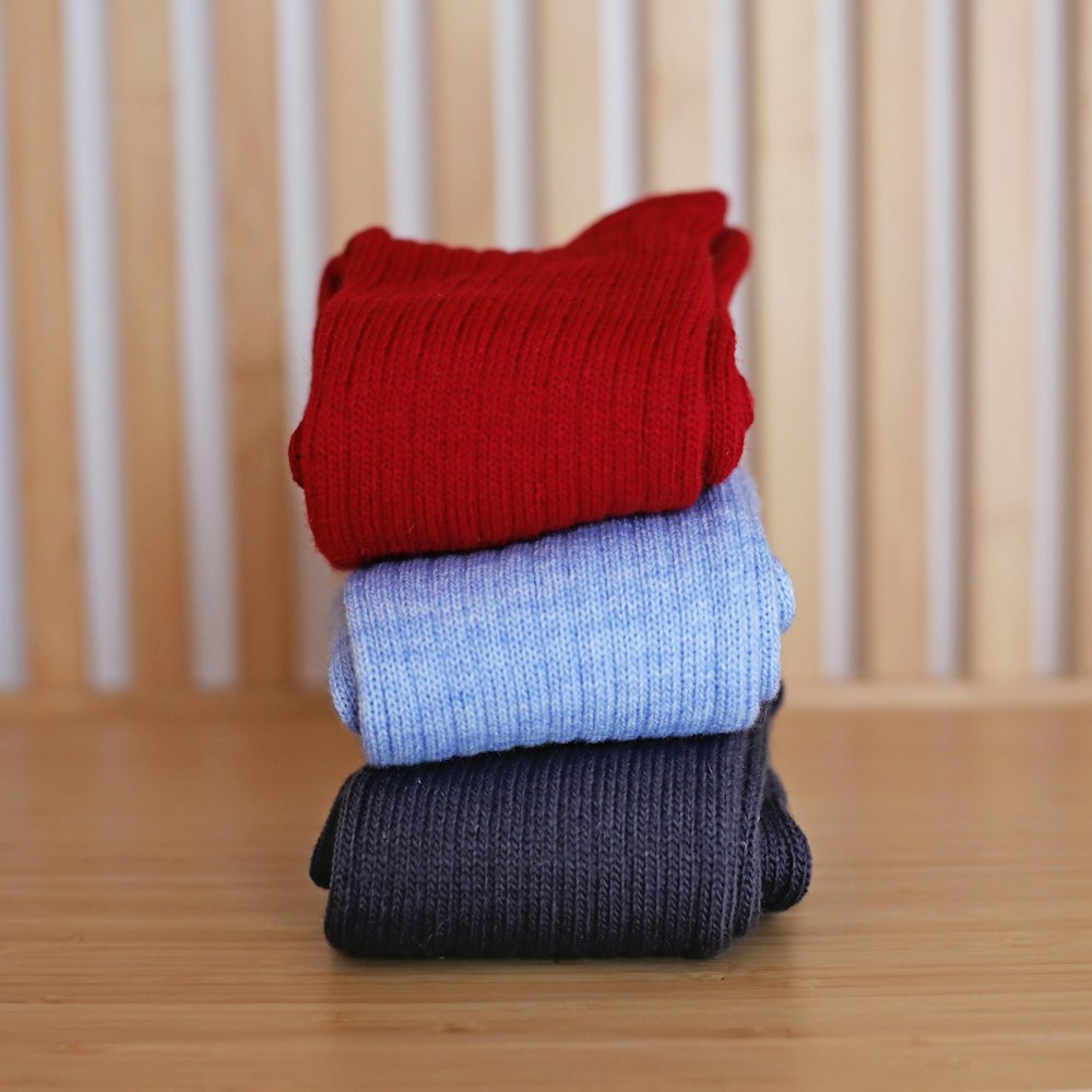 a stack of three socks sitting on top of a wooden table