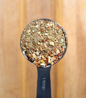 a metal spoon filled with granola on top of a wooden table
