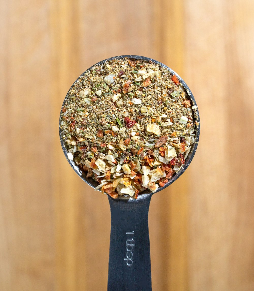 a metal spoon filled with granola on top of a wooden table