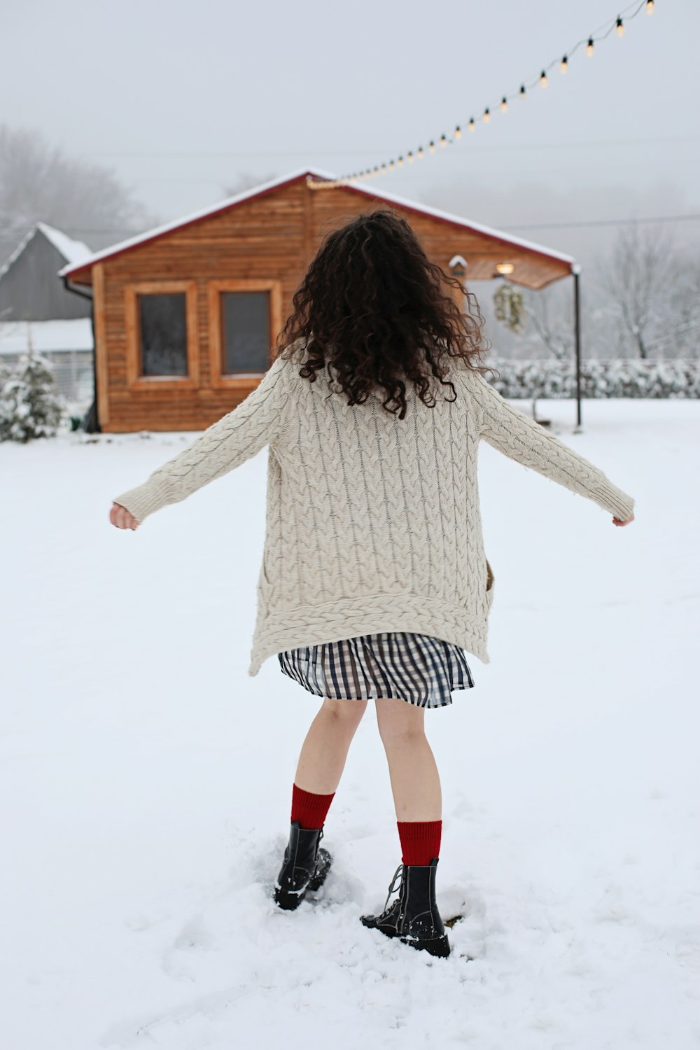 a woman standing in the snow in front of a house