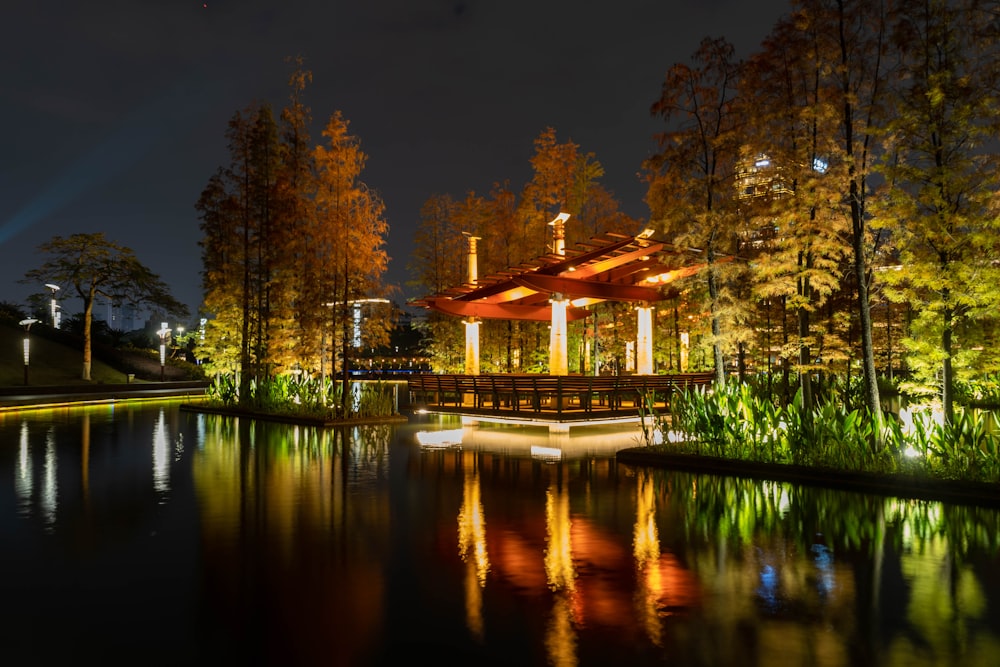a gazebo lit up at night by the water