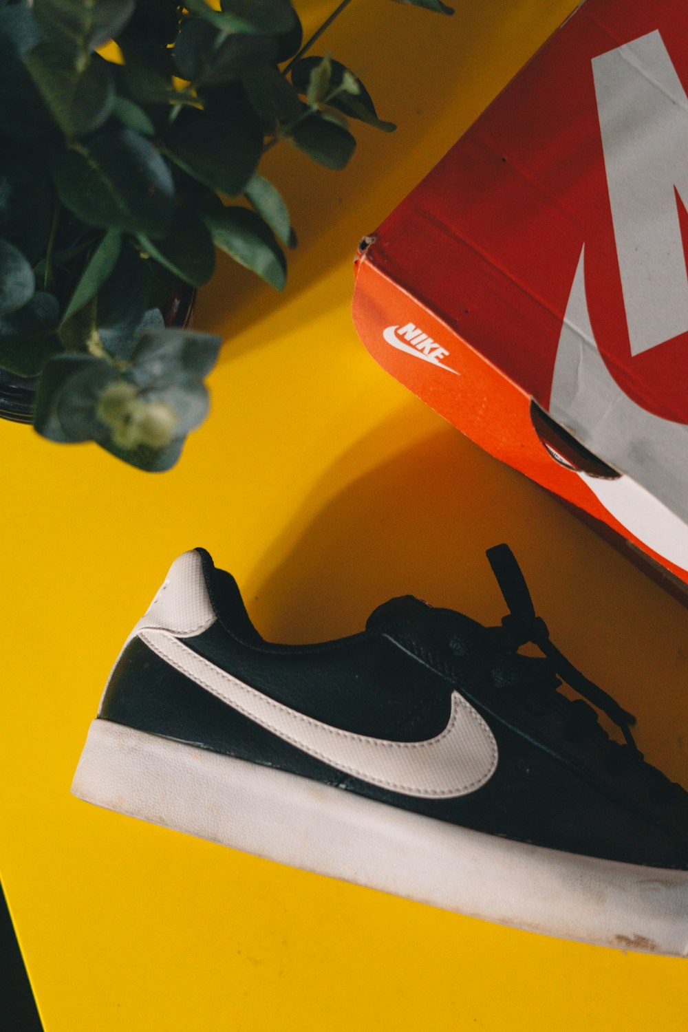 a pair of black and white sneakers sitting on top of a yellow table