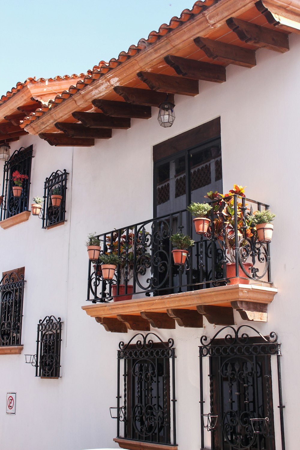 a white building with a balcony and flower pots on the balconies