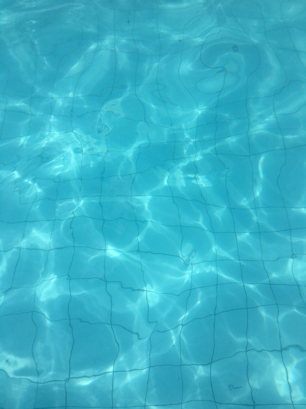 a pool with clear blue water and a tile floor