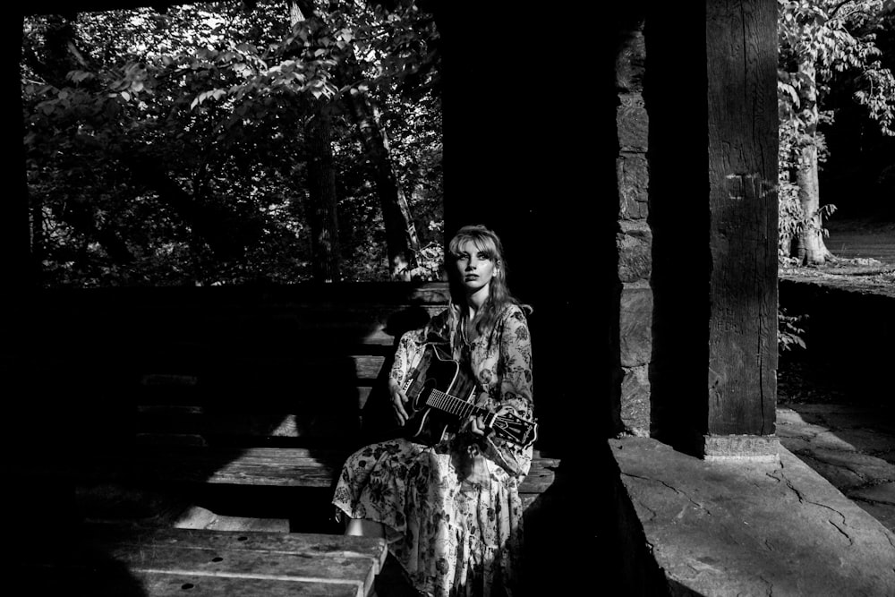 a black and white photo of a woman playing a guitar