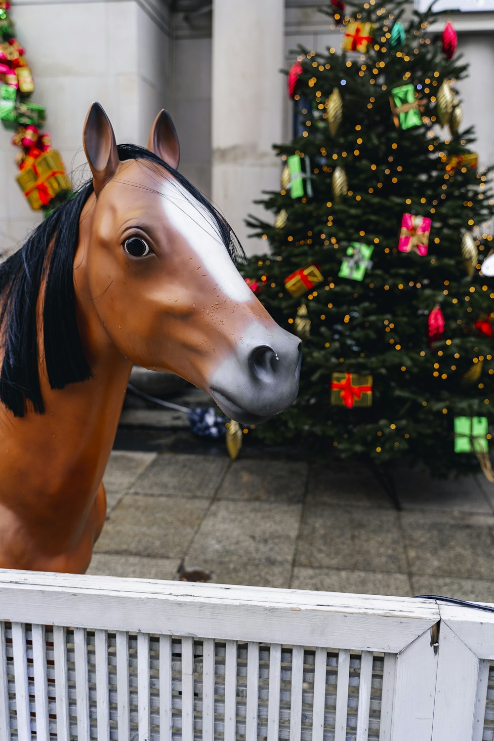 a brown horse standing next to a christmas tree