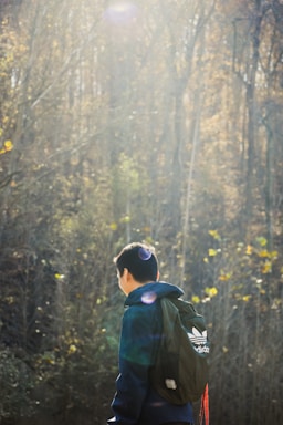A person wearing a lightweight, breathable outdoor jacket standing on a forest trail at sunrise.