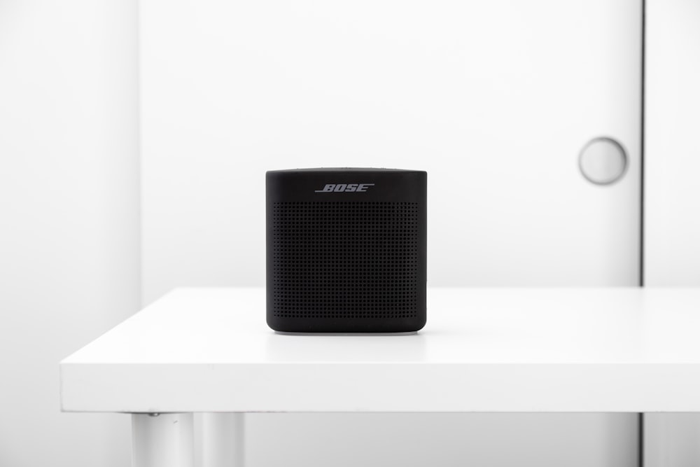 a black speaker sitting on top of a white table