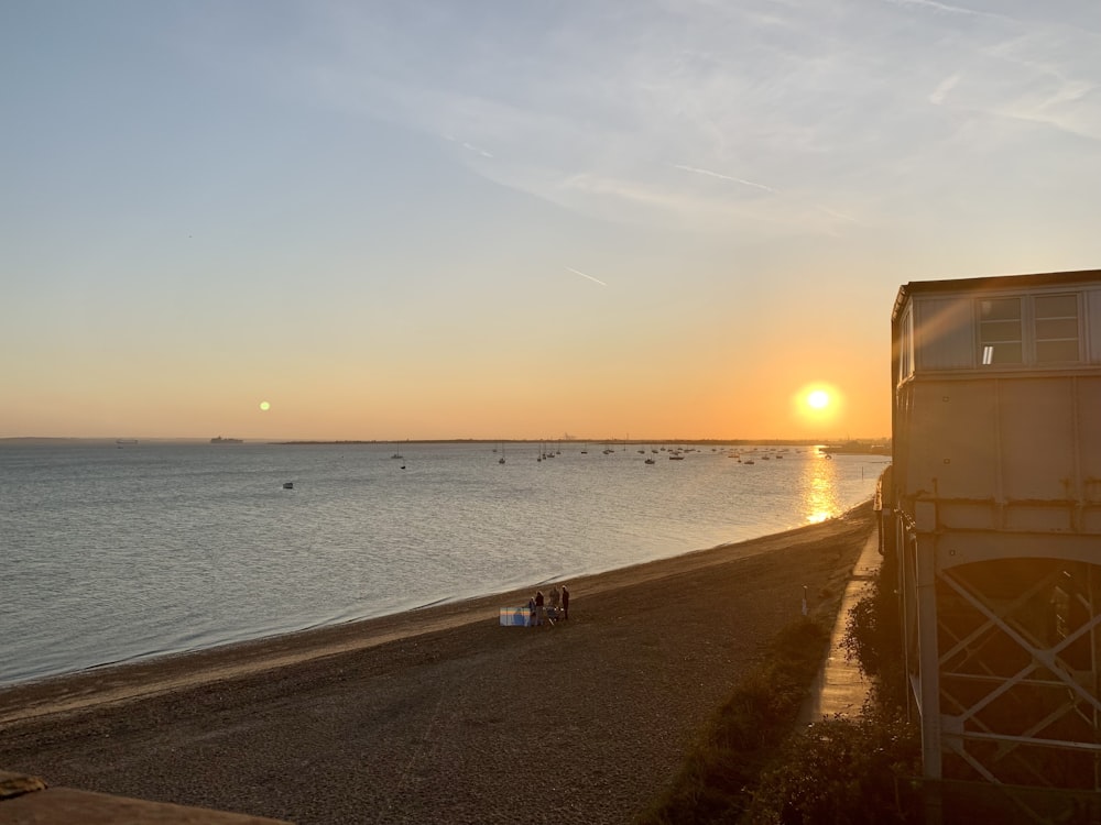 the sun is setting over a beach with people on it