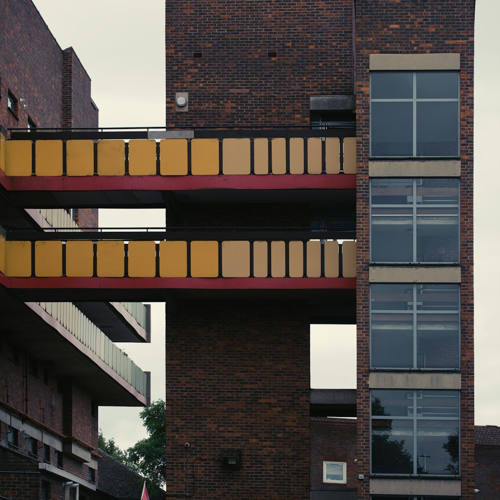 a tall brick building with a red and yellow balcony