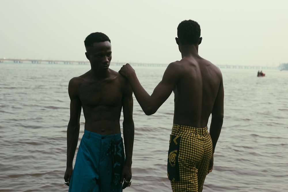 two young men standing next to each other on a beach