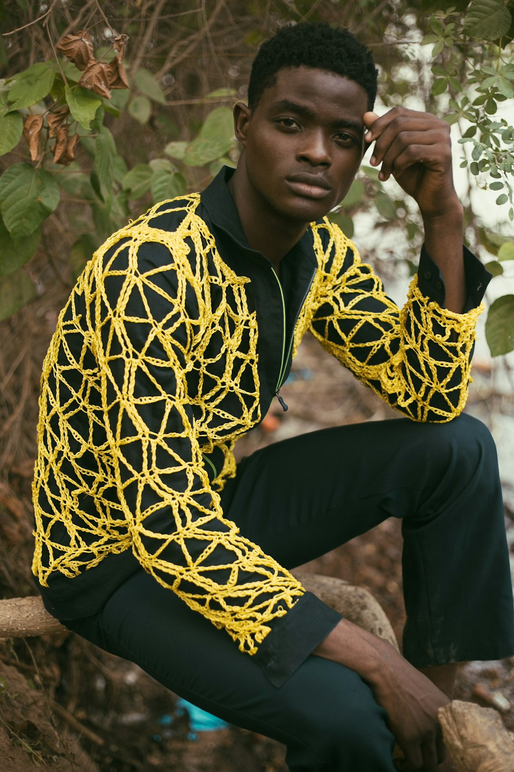 a man sitting on a tree branch wearing a yellow shirt