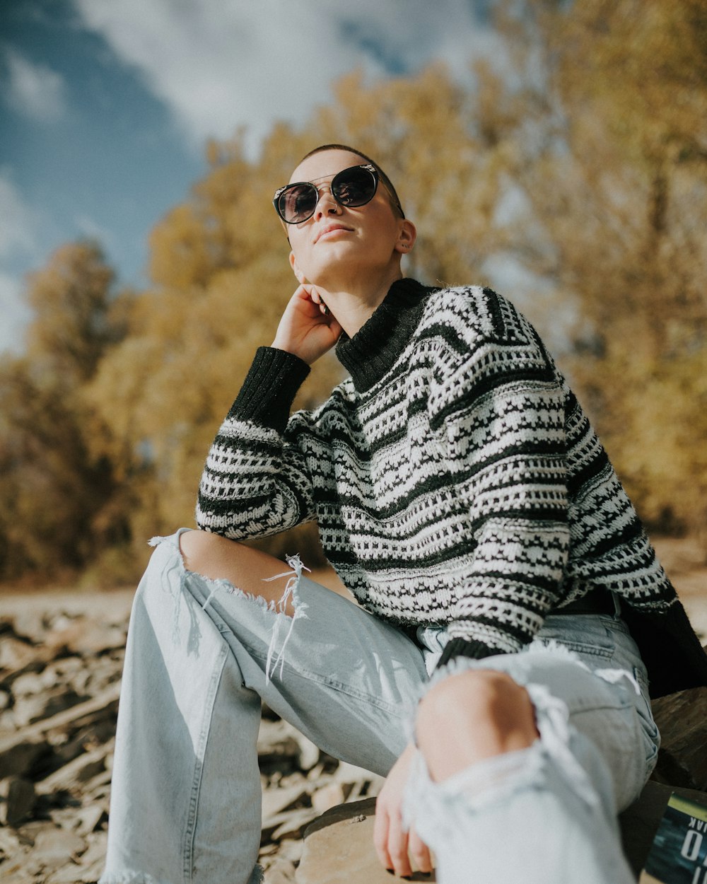 a woman sitting on a rock wearing sunglasses