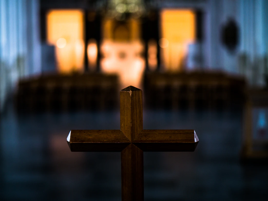 A wooden cross in front of a Catholic church