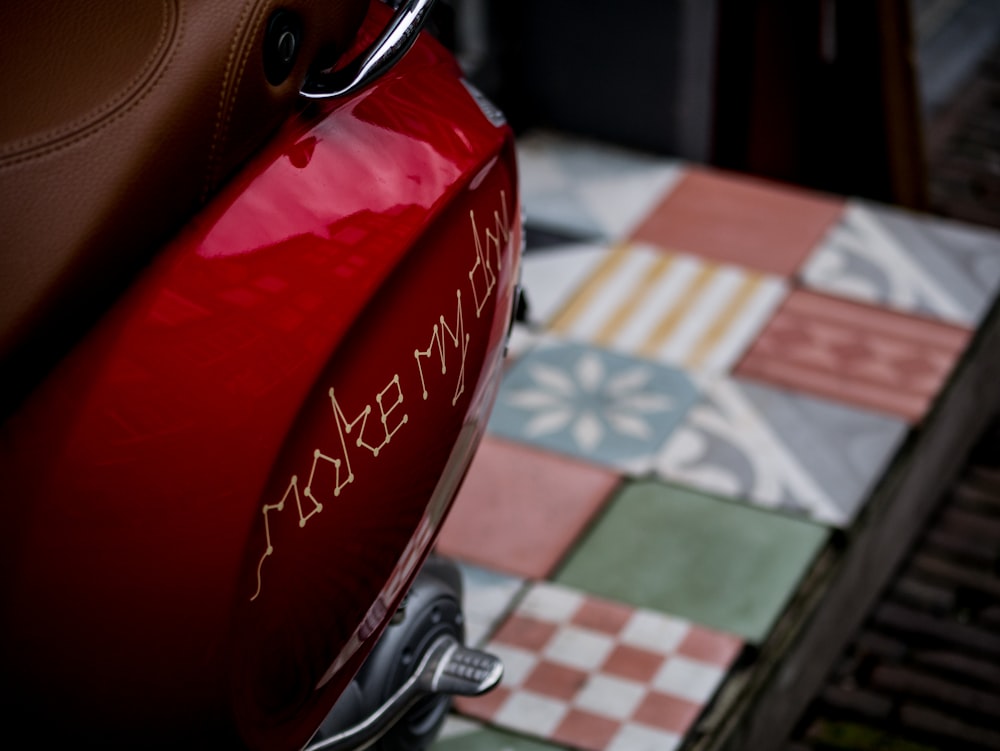 a close up of a red motorcycle parked on a tiled floor