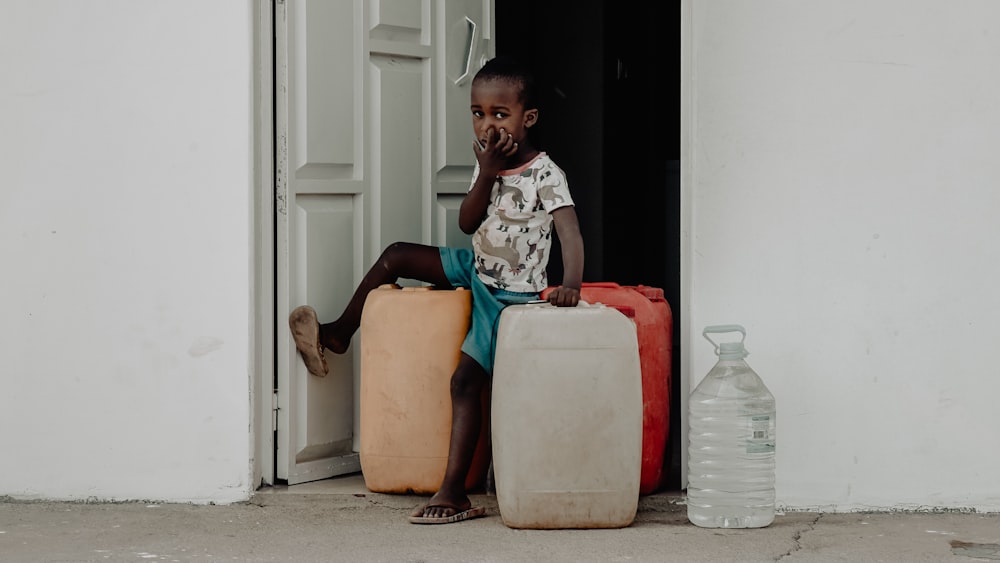 a young boy sitting on top of a pile of luggage