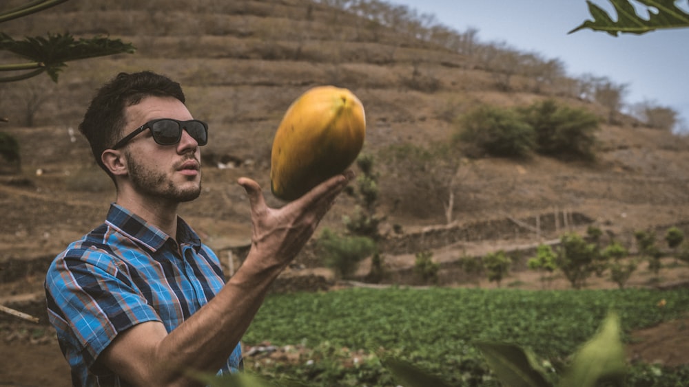 a man holding a banana and a mango in his hand