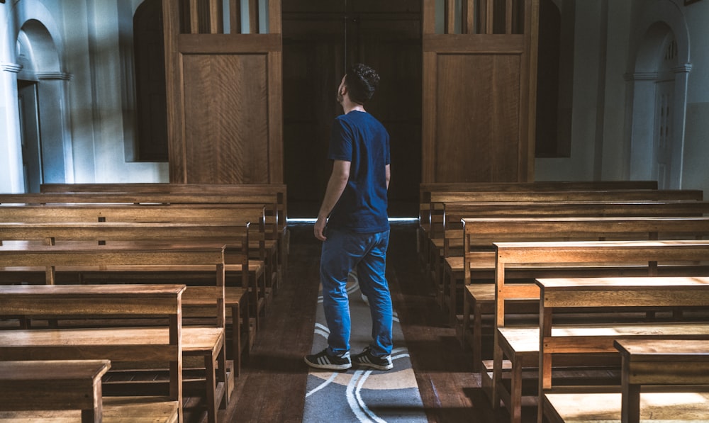 a man standing in a church looking at the pews