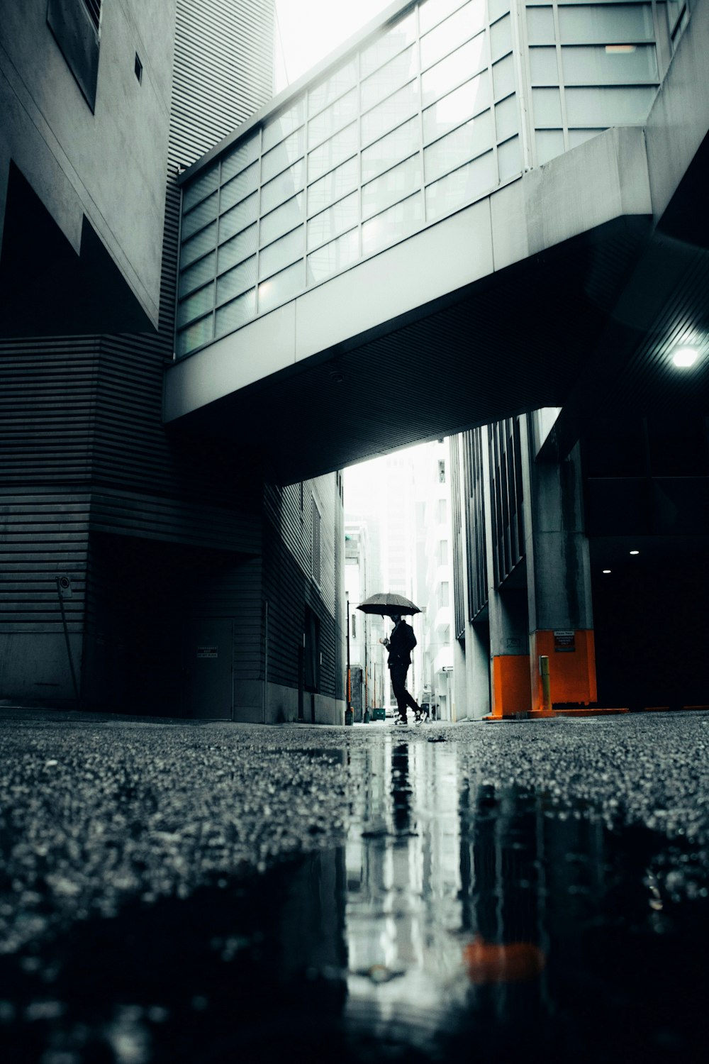 Eine Person mit einem Regenschirm, die unter einer Brücke geht