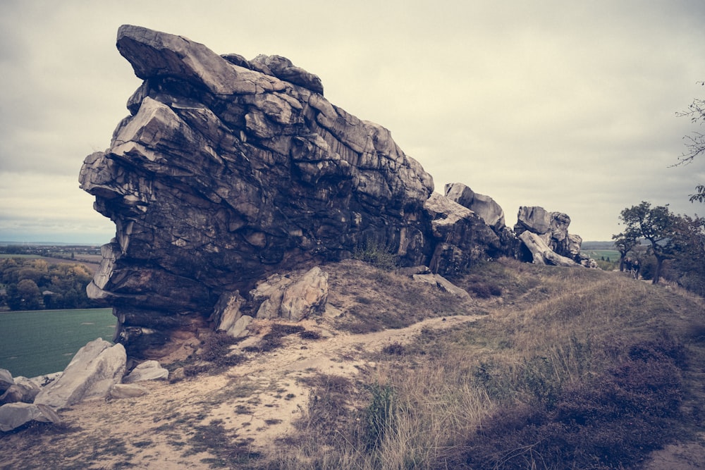 a large rock sitting on the side of a dirt road