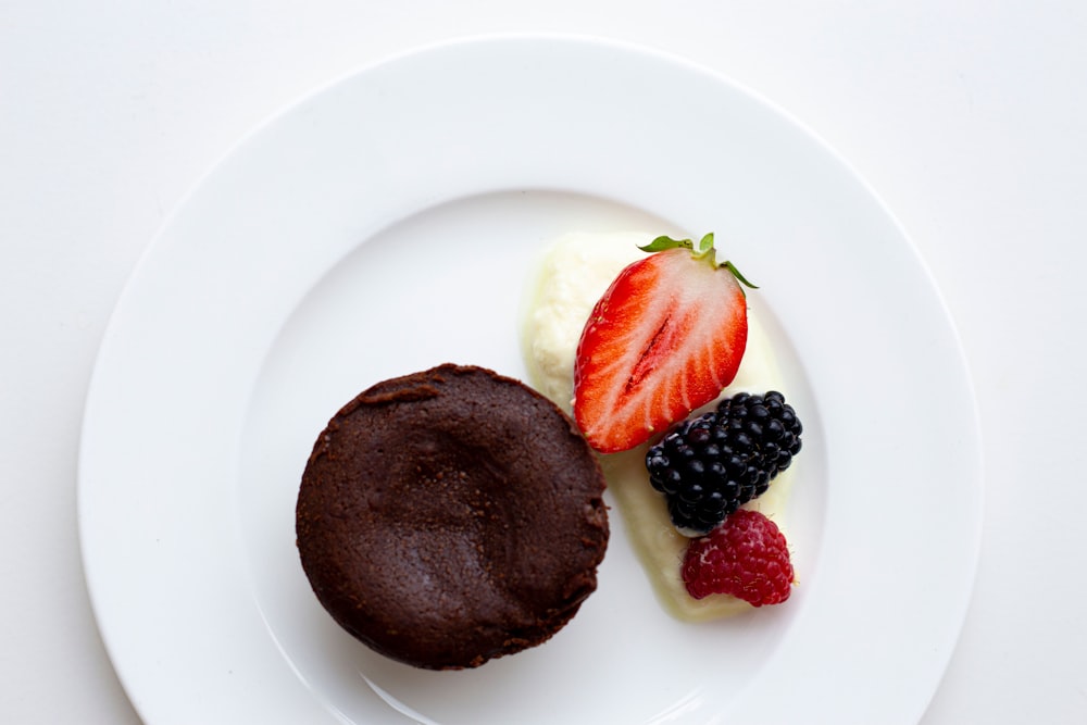 a white plate topped with a chocolate cookie and fruit