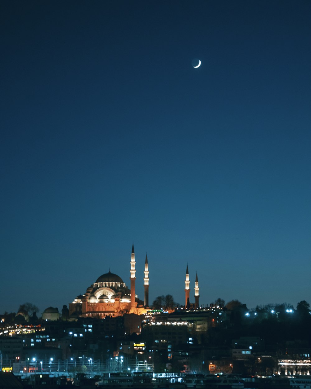 a view of a city at night with the moon in the sky