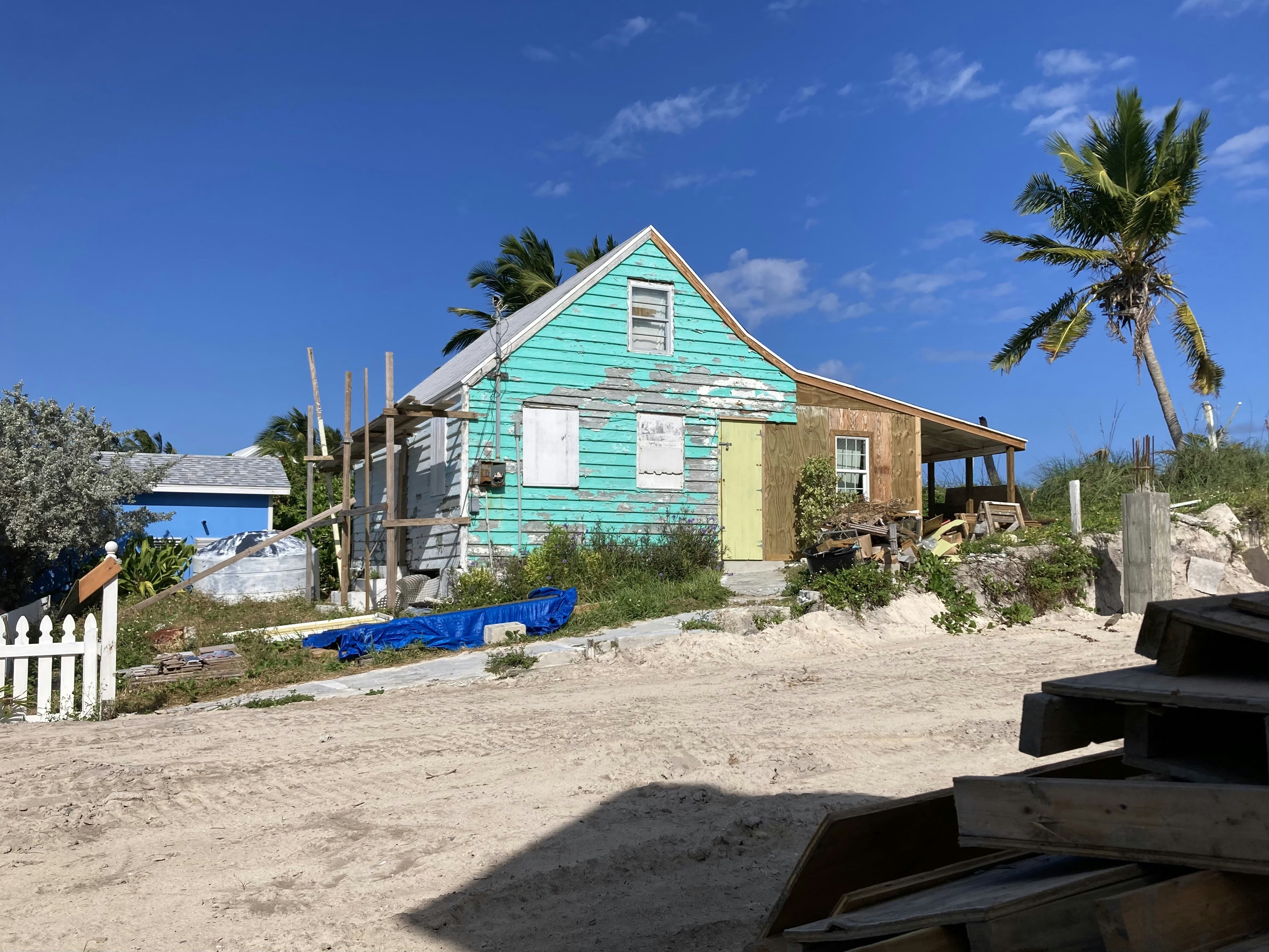 a blue house sitting on top of a sandy beach