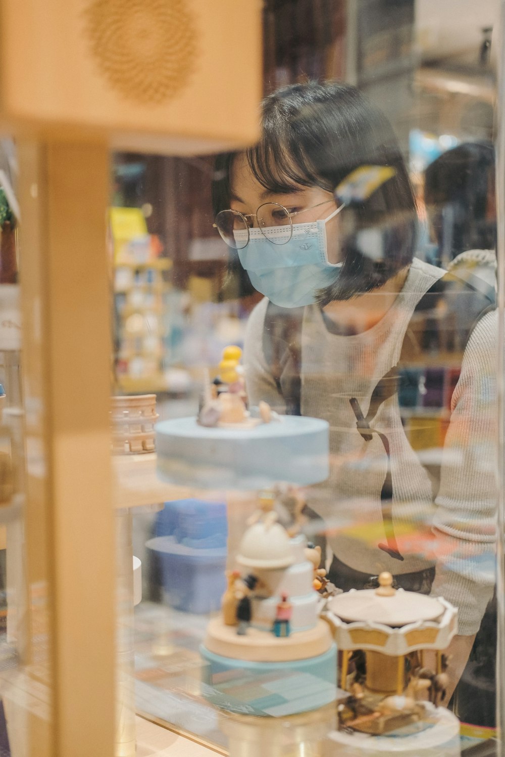 a woman wearing a face mask looking through a window