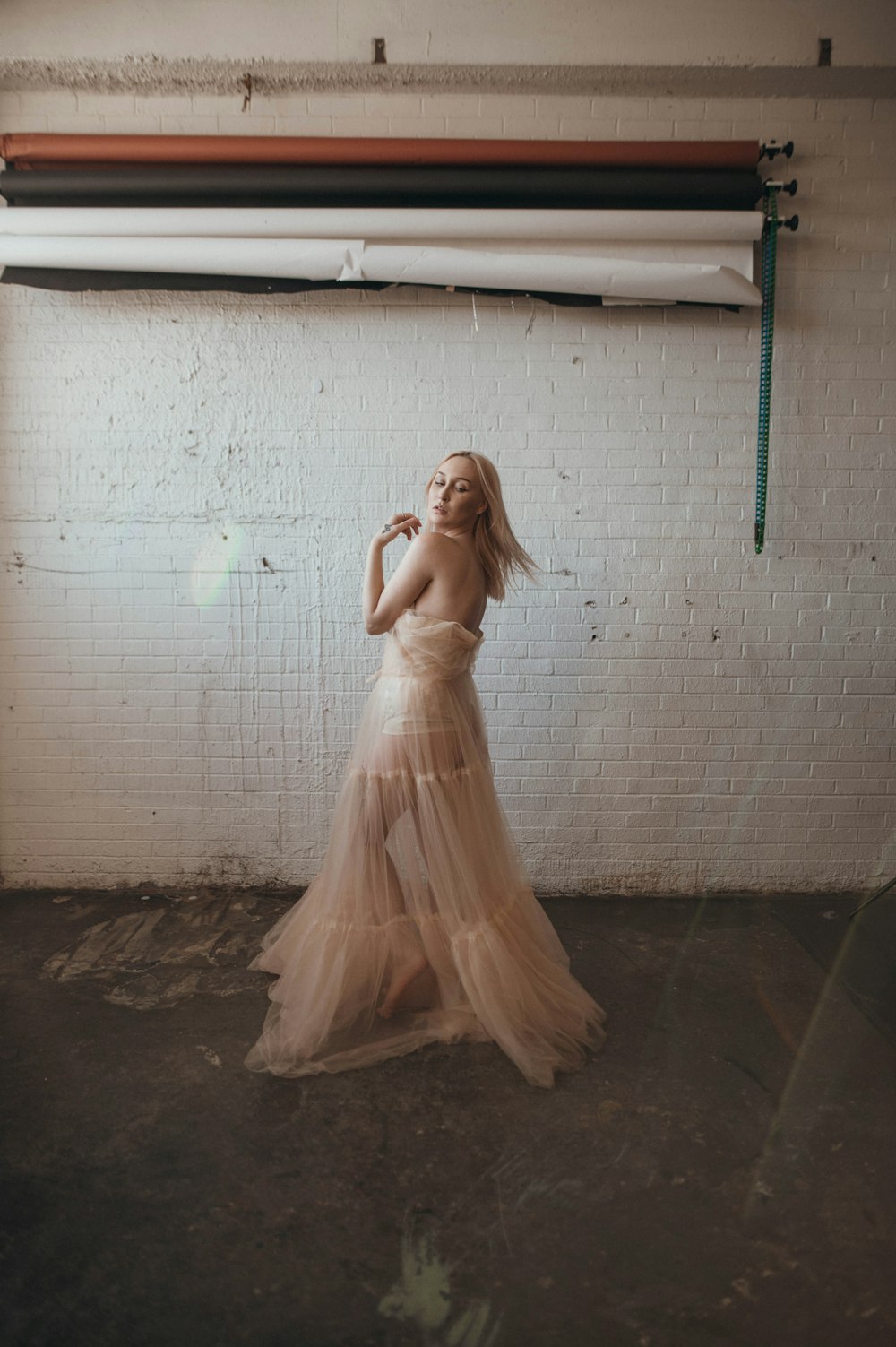 a woman in a dress standing in front of a white brick wall