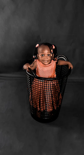 a little girl sitting in a black basket