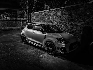a white car parked next to a stone wall