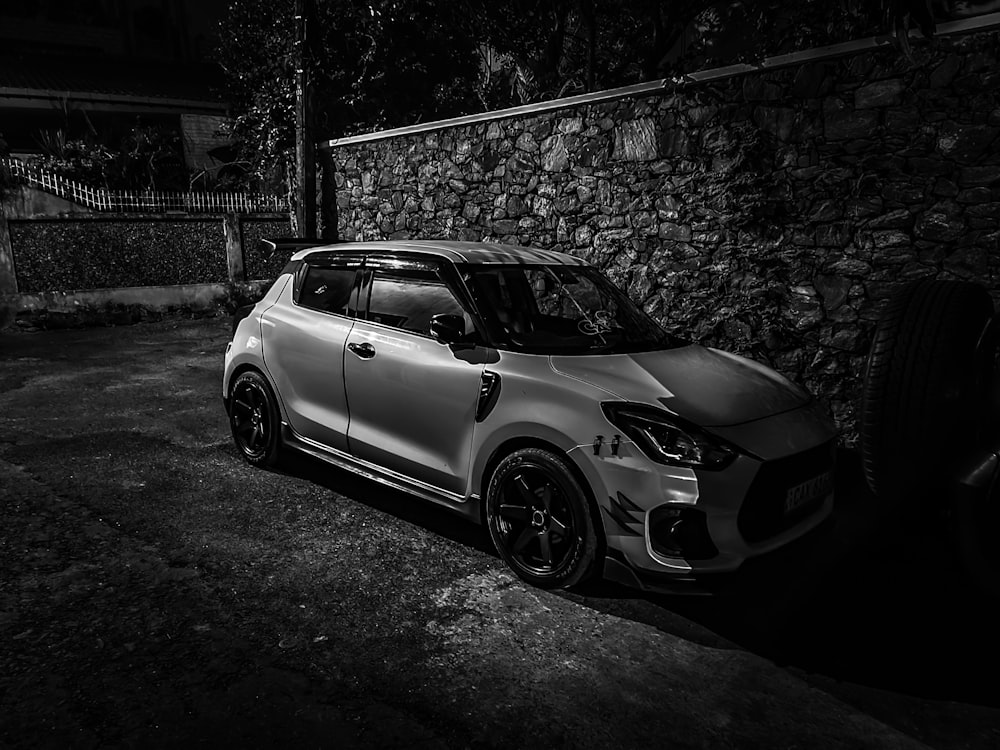 a white car parked next to a stone wall