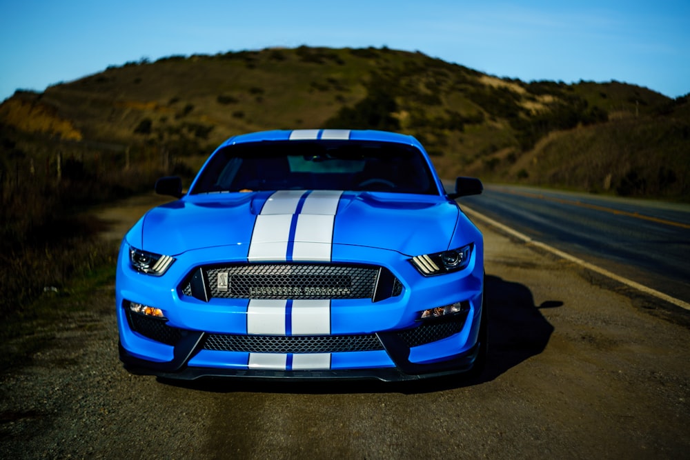 a blue and white mustang parked on the side of a road