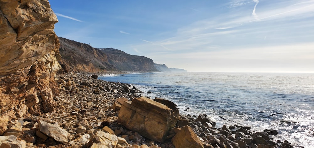 a rocky cliff overlooks the ocean on a sunny day