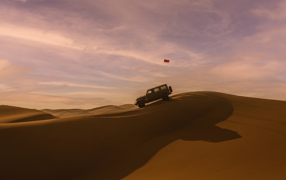 a jeep driving across a desert under a cloudy sky