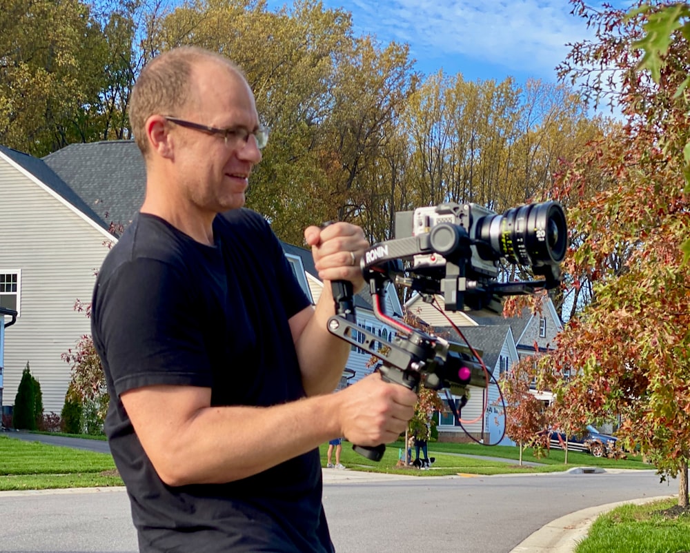 a man holding a camera in front of a house