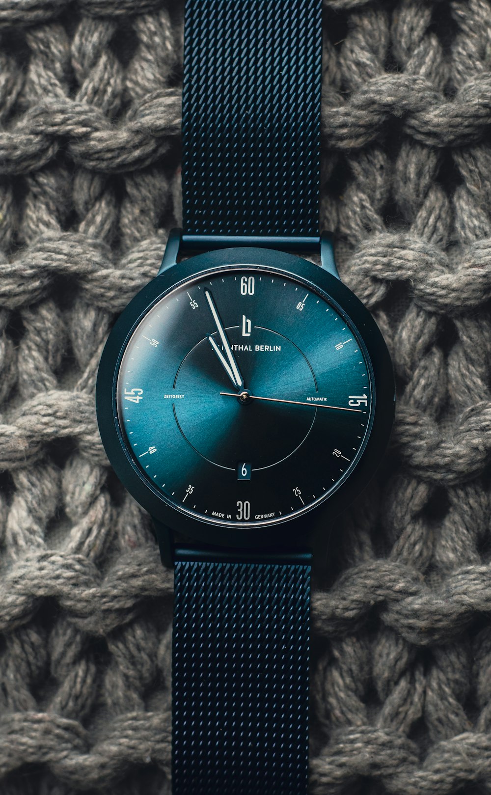 a watch sitting on top of a knitted blanket