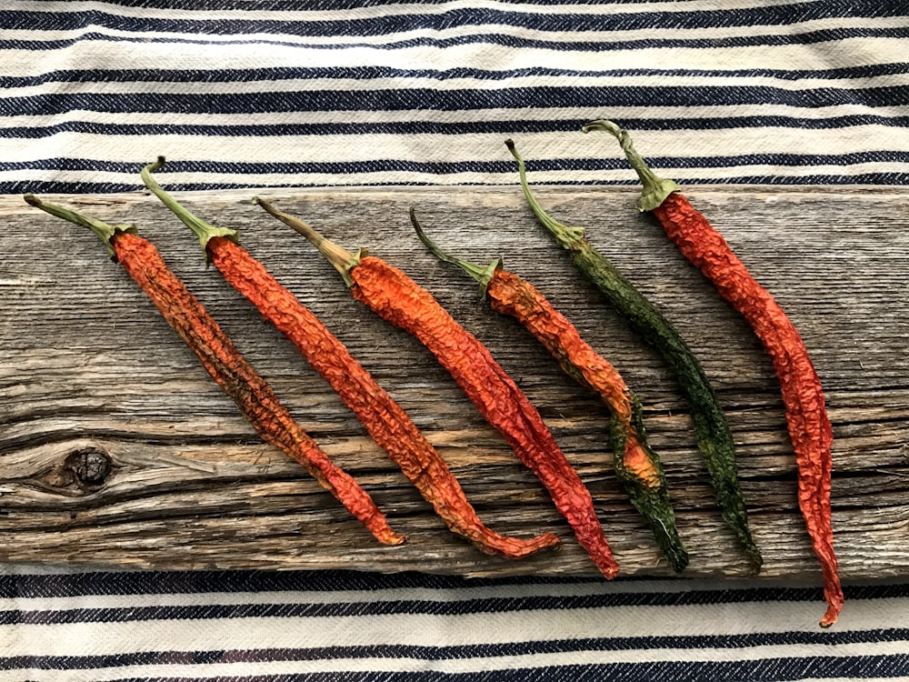 a group of four peppers sitting on top of a wooden board