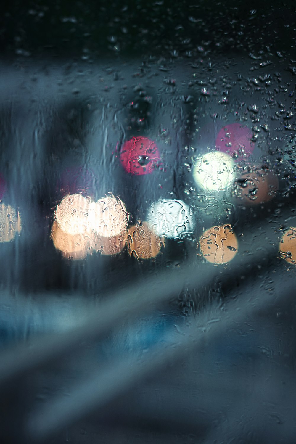 Una vista de una calle de la ciudad a través de una ventana cubierta de lluvia