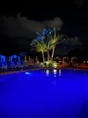 Night view of a pool illuminated with blue underwater lights creating a calm atmosphere.