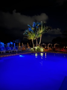Man adjusting pool equipment under soft sky-blue lighting with natural wood accents.