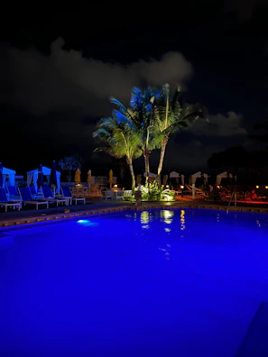 Night view of a pool illuminated with blue underwater lights creating a calm atmosphere.
