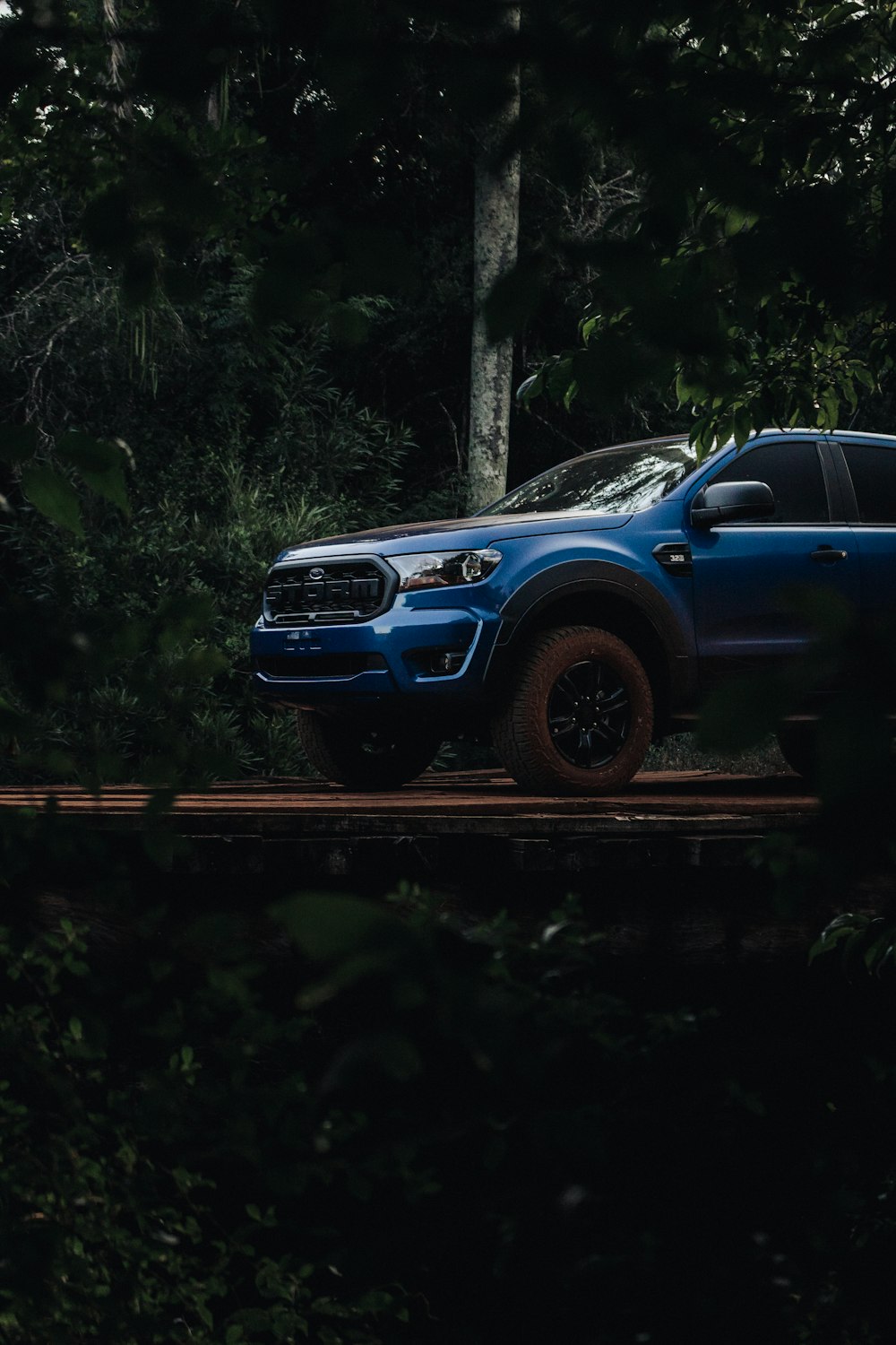 a blue pick up truck parked in the woods