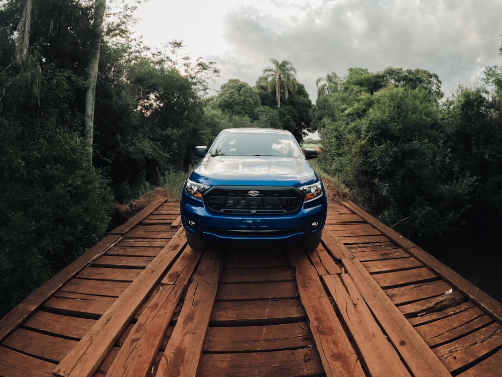 a blue truck is driving on a wooden bridge
