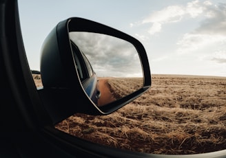 a rear view mirror of a car on a dirt road