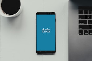 A modern workspace with a coffee cup, notebook, and smartphone showing Colfinex's app interface.