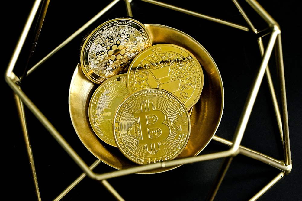 a golden bitcoin sitting on top of a gold plate