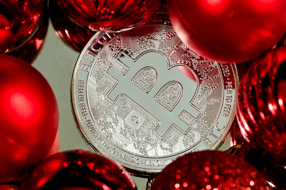 a bitcoin surrounded by red christmas ornaments