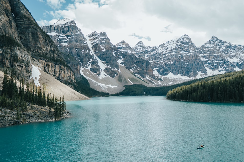 a person in a boat on a lake surrounded by mountains