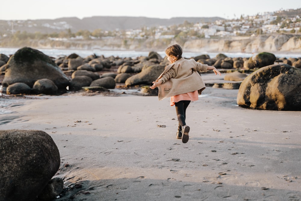 a woman running on a beach with rocks in the background